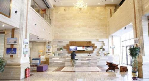 鄂尔多斯GreenTree Inn Ordos Kangbashi District Ulan Mulun Street Branch的一个男人带着一条狗站在宽敞的大厅里。