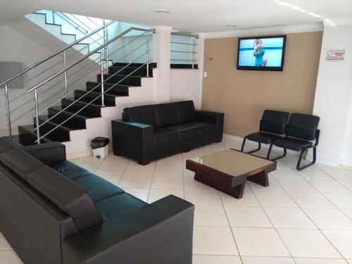 a living room with a couch and a tv at Euro Plaza Hotel - Próximo ao Aeroporto de Goiânia, Santa Genoveva in Goiânia