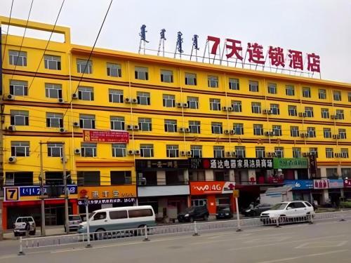 呼和浩特7 Days Inn Hohhot Kaitai Market的黄色的建筑,上面有标志