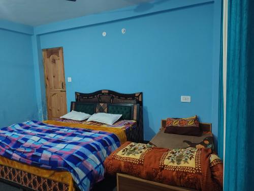 duas camas em um quarto com paredes azuis em Brother's in Mountains em Kasol