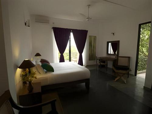 HorawalaMangrove Escapes Resort的一间卧室，配有一张床、一张书桌和一扇窗户