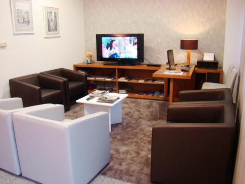 a living room with chairs and a tv and a table at Seculo Hotel in Porto