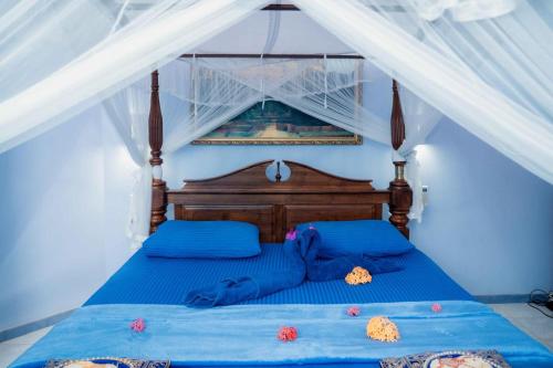 阿鲁特伽马Hotel Blue Sapphire的一间卧室配有一张带蓝色床单和天蓬的床