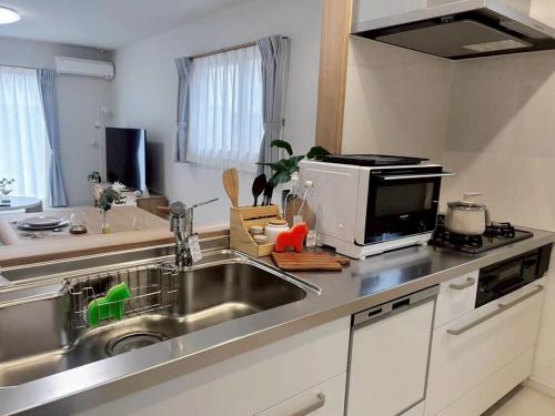 een keuken met een spoelbak en een magnetron bij 馥の森 in Kumamoto