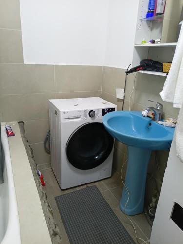 Eine Waschmaschine steht neben einem blauen Waschbecken. in der Unterkunft Zebra Guest House in Ulaanbaatar