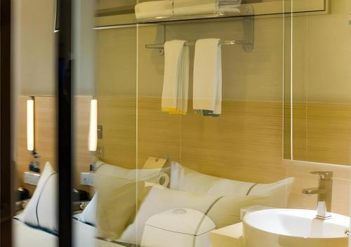 ein Badezimmer mit einem Spiegel, einem Waschbecken und Handtüchern in der Unterkunft City Comfort Inn Guilin Lingui Jinshan Square in Lingui