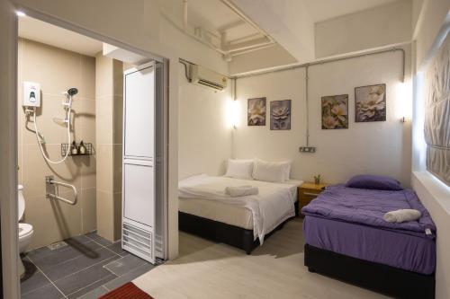 a small room with two beds and a shower at Kenny Hill Boutique Hotel near Borneo Medical Centre Kuching in Kuching