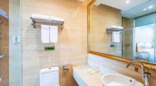 un bagno con lavandino, specchio e WC di Vienna Classic Hotel Qingdao Huangdao a Huangdao