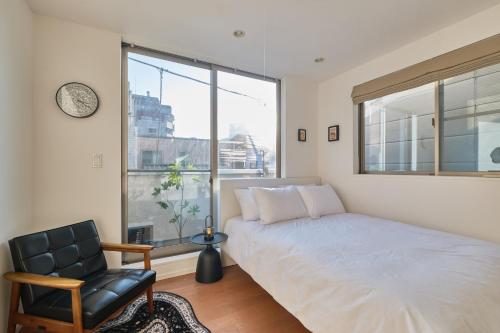 a bedroom with a bed and a chair and a window at Mint House Ebisu - 3 Story, Artsy & Modern Home in Shibuya in Tokyo