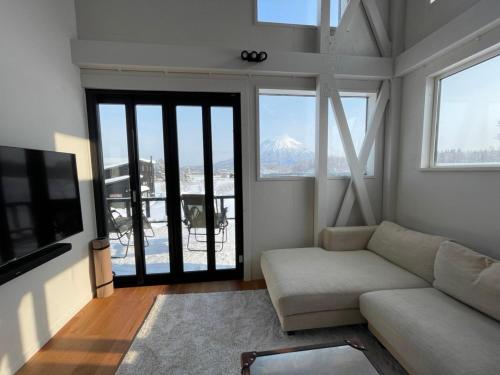 a living room with a couch and a tv at Straddie House Niseko in Niseko