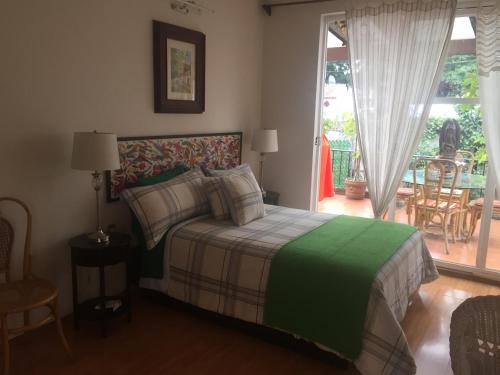 a bedroom with a bed with a green and white blanket at Maria Del Alma House in Mexico City