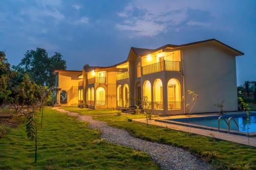 a villa with a swimming pool at night at Evaan Litchi Orchards and Resorts, Corbett in Rāmnagar