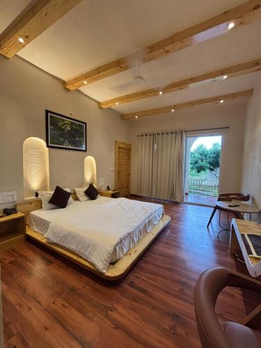a large bedroom with a bed and a large window at Evaan Litchi Orchards and Resorts, Corbett in Rāmnagar