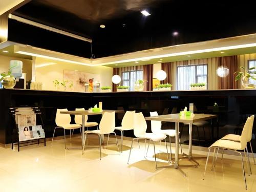 a restaurant with white chairs and tables and windows at Jinjiang Inn Xiamen Railway Station in Xiamen