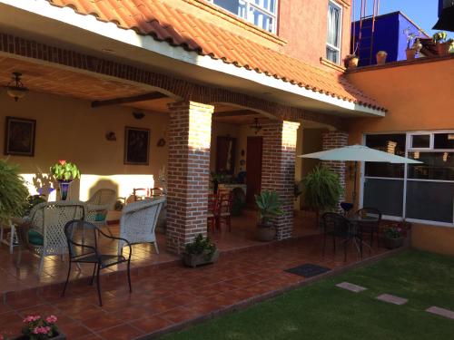 a patio with chairs and tables and an umbrella at Maria Del Alma House in Mexico City