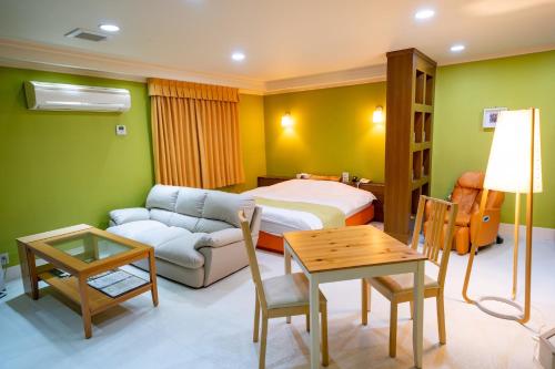 a bedroom with a bed and a couch and a table at ホテルパティオ in Suwa