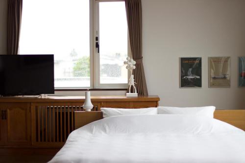 a bedroom with a white bed and a flat screen tv at Seaside Inn Hokuto in Hokuto