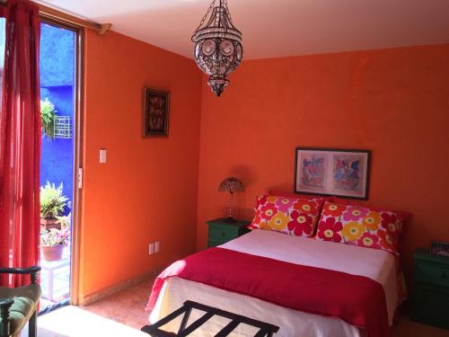a bedroom with orange walls and a bed and a chandelier at Maria Del Alma House in Mexico City