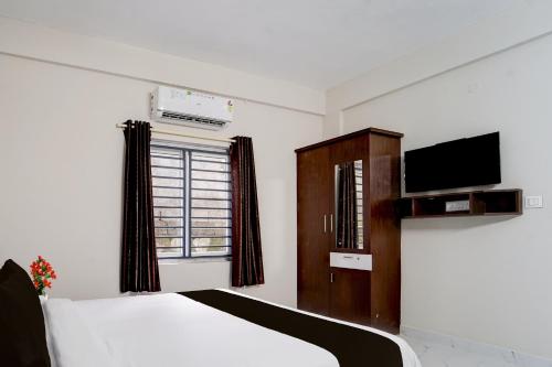 阿鲁法Collection O Aluva Kinfra Hi-Tech Park的一间卧室配有一张床、一台电视和一个橱柜