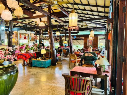 a person sitting at a table in a room with flowers at Sala Homestay in Ban Mae Nai
