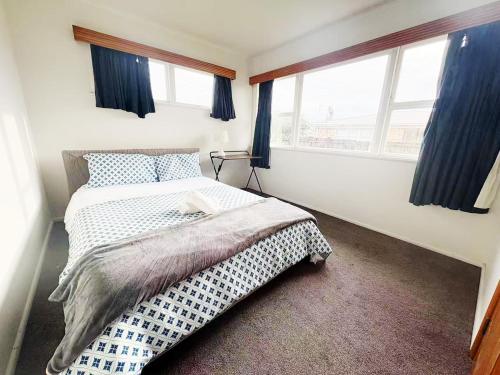 a bedroom with a bed and two windows at Peaceful Home Near Gardens, University & Downtown in Hamilton