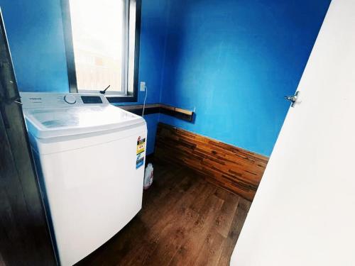 a small blue kitchen with a refrigerator and a window at Peaceful Home Near Gardens, University & Downtown in Hamilton