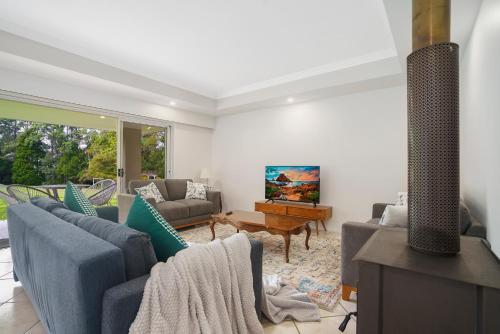 a living room with blue couches and a television at Hideaway with us, on Tamborine Mountain in Mount Tamborine