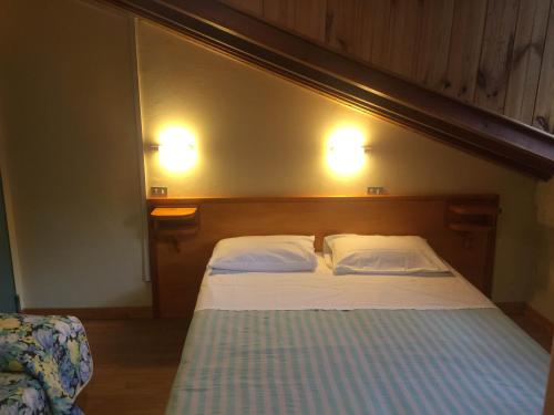 a bed in a bedroom with two lights on the wall at Val Del Rio in Fiumalbo