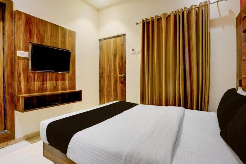a bedroom with a bed and a tv on the wall at Super Townhouse Andheri Sakinaka Metro Formerly Hotel Amour in Mumbai