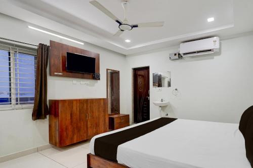 a bedroom with a bed and a tv on the wall at Collection O Mini Bypass Nellore Road Formerly AMR Guest Inn in Nellore