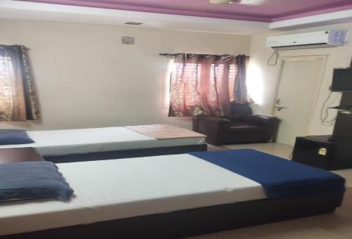 una habitación de hotel con dos camas y un sofá en POP 84142J Krishnapatnam Grand Inn, en Muttukūru