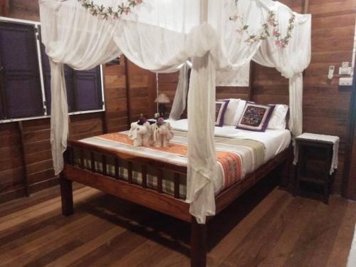 ein Schlafzimmer mit einem Himmelbett in der Unterkunft ออร์คิดไฮบิสคัส เกสท์เฮ้าส์ in Sukhothai
