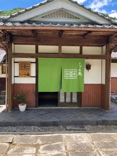a building with a green banner in front of it at ゲストハウス こごみ庵 in Shikokuchuo