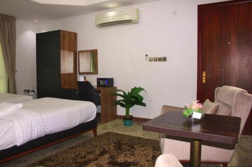 ein Hotelzimmer mit einem Bett, einem Schreibtisch und einem Tisch in der Unterkunft Nermeam in Muscat
