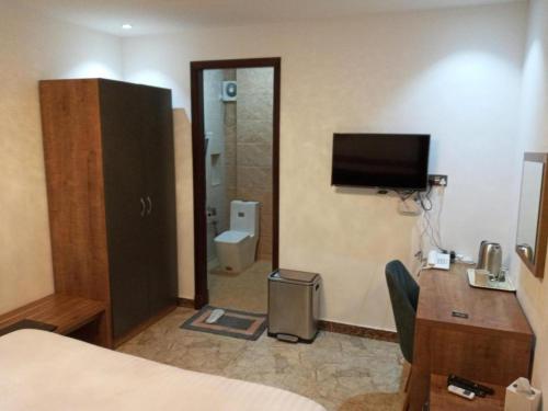 ein Hotelzimmer mit Bett, Schreibtisch und Fernseher in der Unterkunft Nermeam in Muscat