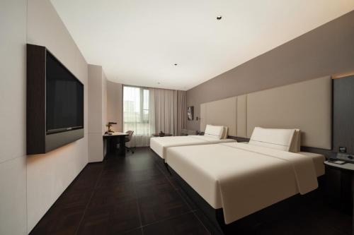 ein Hotelzimmer mit zwei Betten und einem Flachbildfernseher in der Unterkunft Atour Hotel Shanghai The Bund Yuyuan Subway Station in Shanghai