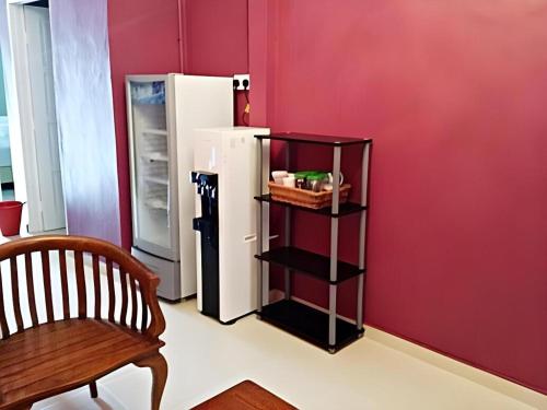 a red room with a refrigerator and a chair at HOTEL BAJET MUGHOH SENGOTI in Kampong Gong Kempas