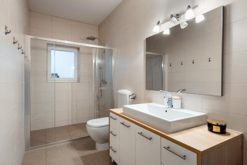 a bathroom with a sink and a toilet and a mirror at Utković Beachfront Apartments in Vrsi