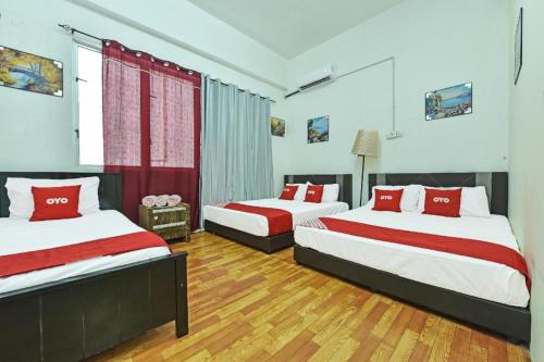 una camera da letto con due letti con cuscini rossi di OYO 90431 CZ Hotel a Pasir Puteh