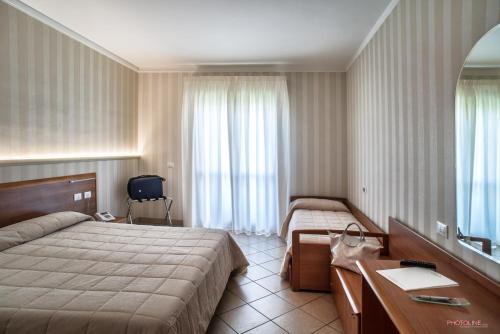 a hotel room with two beds and a desk and a mirror at Hotel Villa Giulia in Ciampino