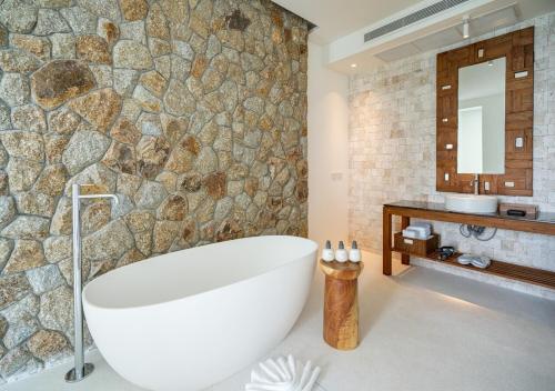 un bagno con ampia vasca e parete in pietra di Cape Azure Resort Samui by Thalsea a Plai Laem