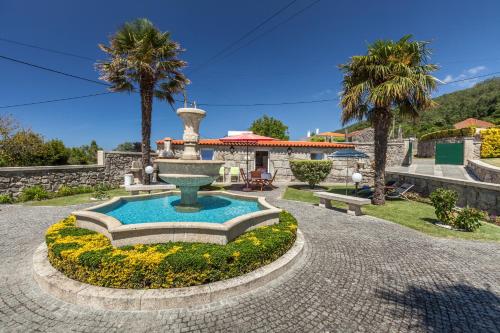 a fountain in the middle of a courtyard with palm trees at Casa do Chafariz in Viana do Castelo