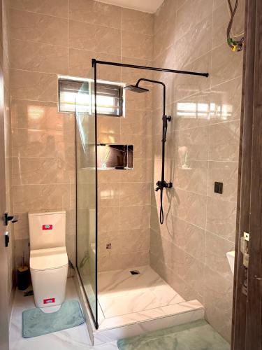 a bathroom with a glass shower with a toilet at Cozy Apartment in Lekki in Lekki