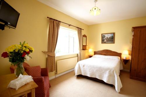 1 dormitorio con 1 cama y un jarrón de flores en Brooklodge Bed and Breakfast en Westport