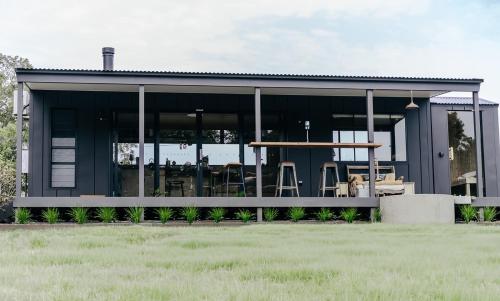 a house with large glass windows and a table at Riverfront Luxury Stay Tiny House Sauna and Bath in Old Bar
