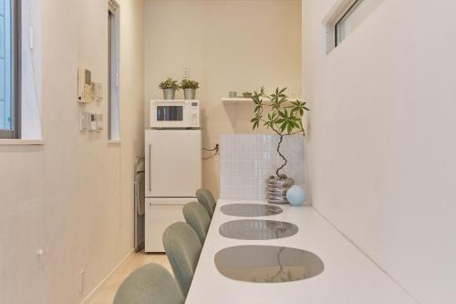 a white kitchen with a long table and chairs at Mint House Ebisu - 3 Story, Artsy & Modern Home in Shibuya in Tokyo
