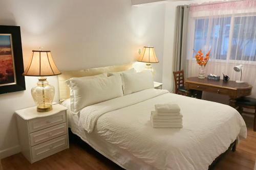 Un dormitorio con una cama blanca con dos lámparas y un escritorio. en The Nesting Suite, en Surrey