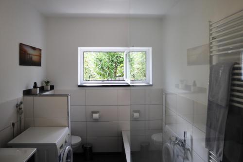 a white bathroom with a window and a toilet at Ferienwohnung Dicke Linde, 55qm in Schmallenberg