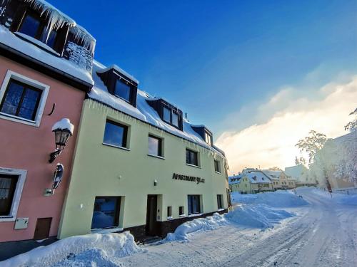 a building with snow on the ground next to a street at APARTMÁNY 91 Boží Dar in Boží Dar