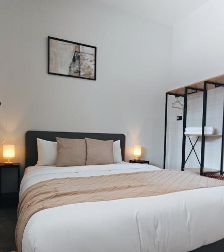 a bedroom with a large white bed with two lamps at How Hide Space in Kanchanaburi City